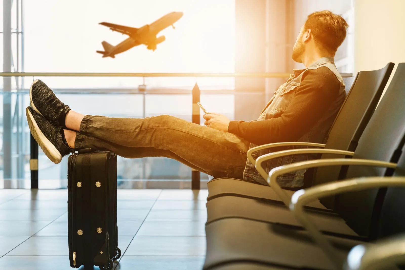 تغییر تاریخ رایگان بلیط امارات؛ قانون جدید و بدون محدودیت (۲۰۲۶) 2 traveler waiting airport boarding gate plane