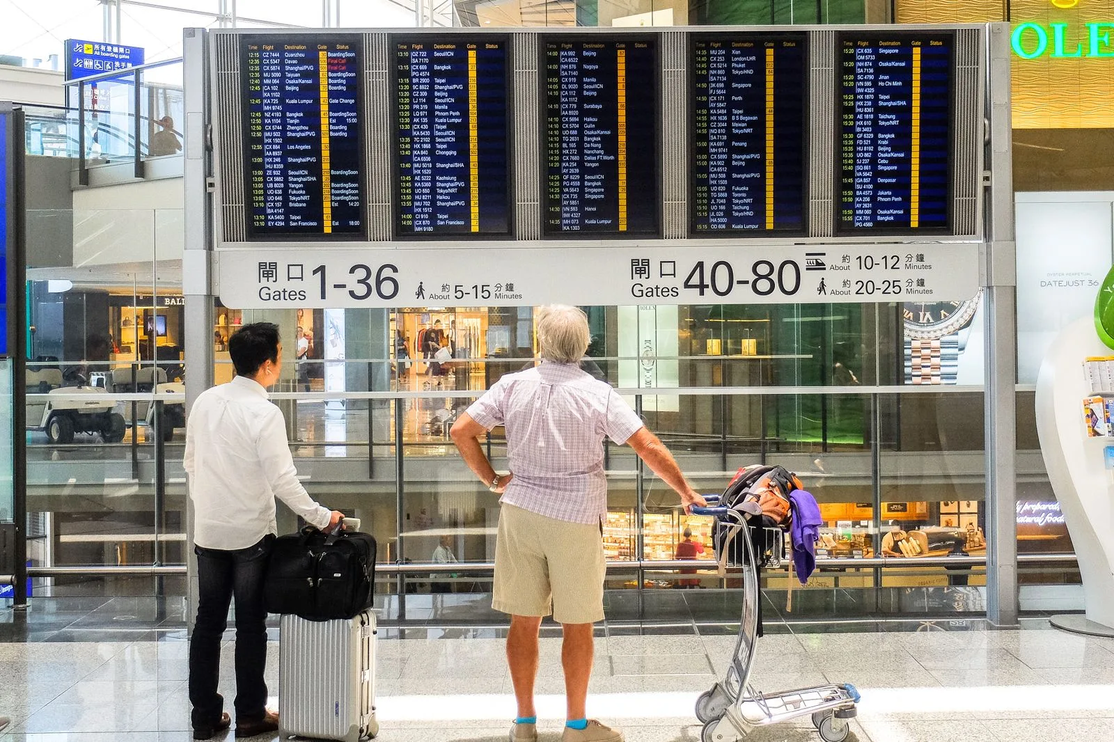 وضعیت پرواز به دبی امروز؛ برنامهی پروازها از ۲۴ اوت به حالت عادی بازگشت 2 travelers airport terminal luggage walking